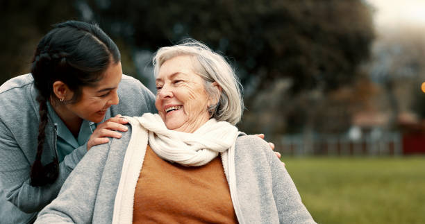Carer laughing with an older woman outdoors